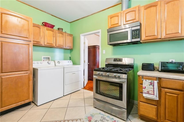 kitchen with washer and dryer, light tile patterned flooring, ornamental molding, and stainless steel appliances