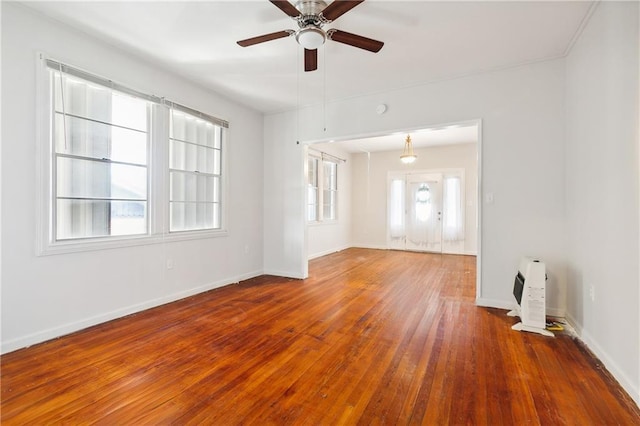 spare room with hardwood / wood-style flooring, ceiling fan, and heating unit