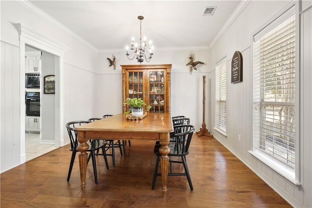 dining area featuring hardwood / wood-style flooring, crown molding, and an inviting chandelier