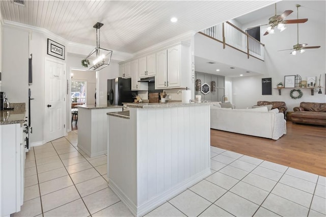 kitchen with black fridge, crown molding, decorative light fixtures, white cabinets, and light tile patterned flooring