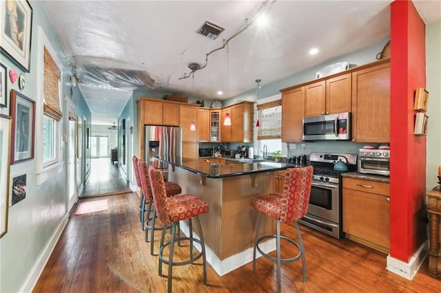 kitchen featuring dark wood-type flooring, a center island, stainless steel appliances, and a healthy amount of sunlight