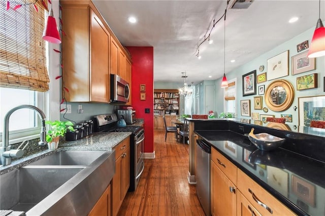 kitchen featuring decorative light fixtures, stainless steel appliances, dark wood-type flooring, and sink