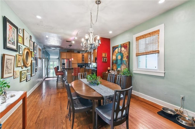 dining area featuring a wealth of natural light, light hardwood / wood-style flooring, and an inviting chandelier