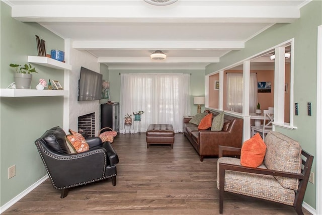 sitting room with beamed ceiling, wood-type flooring, and a large fireplace