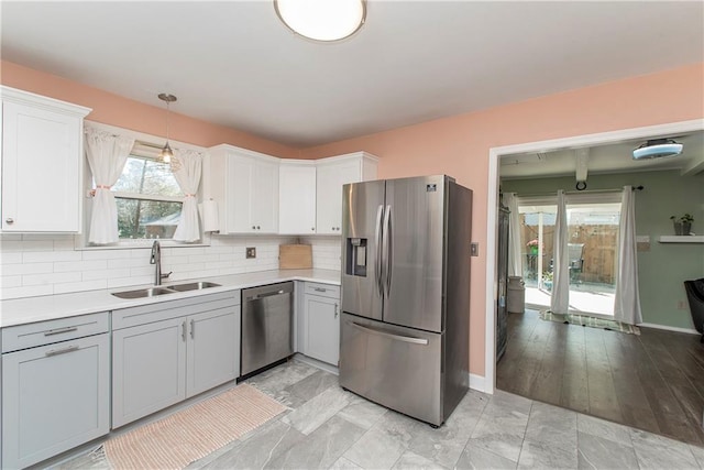 kitchen with gray cabinetry, stainless steel appliances, sink, decorative light fixtures, and white cabinetry