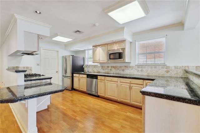 kitchen featuring sink, light hardwood / wood-style flooring, appliances with stainless steel finishes, kitchen peninsula, and a breakfast bar area