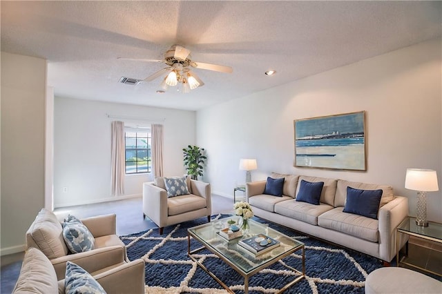 living room featuring dark colored carpet, ceiling fan, and a textured ceiling