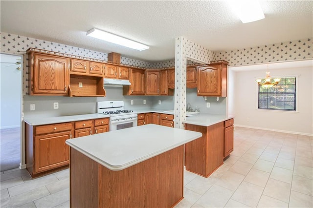 kitchen featuring white gas range, a center island, an inviting chandelier, pendant lighting, and a textured ceiling