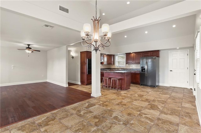 kitchen with a center island, stainless steel fridge, a breakfast bar, ceiling fan with notable chandelier, and light wood-type flooring