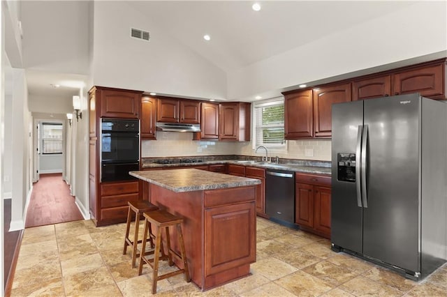 kitchen featuring a breakfast bar, backsplash, high vaulted ceiling, a kitchen island, and stainless steel appliances