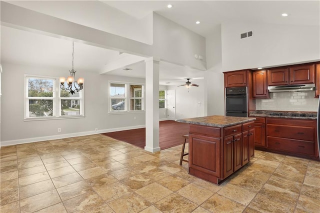 kitchen featuring high vaulted ceiling, pendant lighting, a kitchen island, black appliances, and ceiling fan with notable chandelier