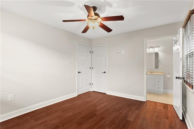 unfurnished bedroom with dark hardwood / wood-style floors, ceiling fan, sink, and ensuite bathroom