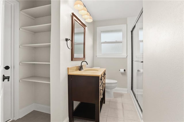 bathroom with tile patterned flooring, vanity, toilet, and an enclosed shower