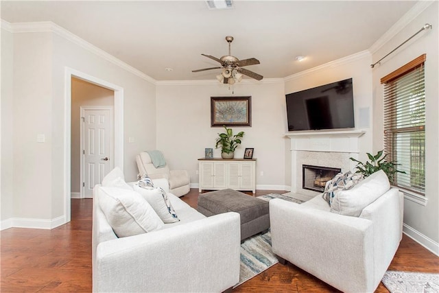 living room with a fireplace with flush hearth, baseboards, a ceiling fan, wood finished floors, and crown molding