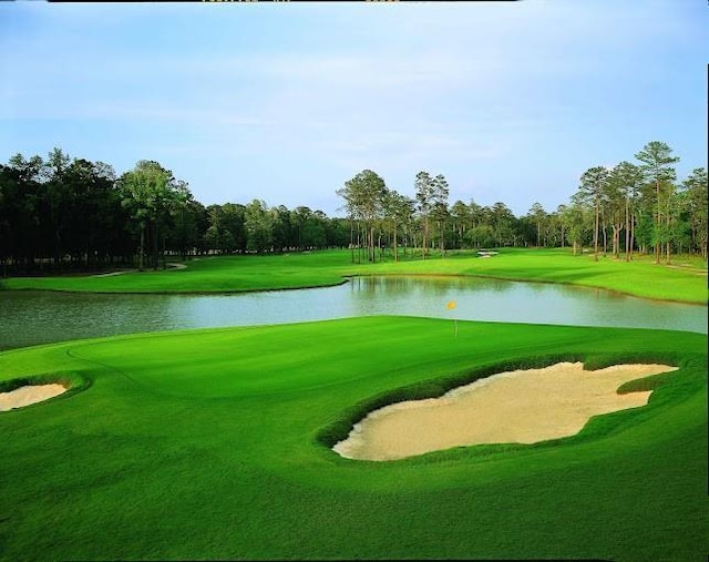 view of property's community with a lawn, a water view, and golf course view