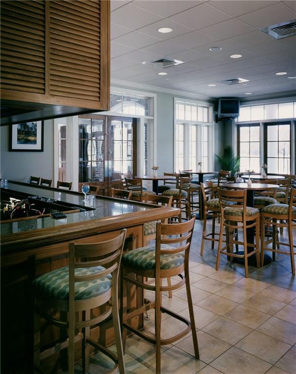 tiled dining area featuring crown molding and visible vents