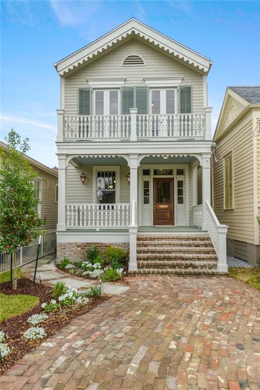 view of front of home featuring covered porch, a balcony, and fence