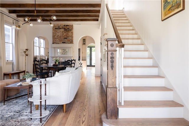 interior space featuring arched walkways, beam ceiling, hardwood / wood-style floors, and stairs