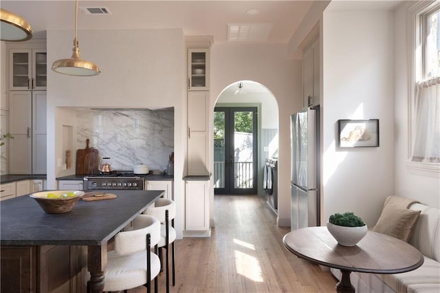 kitchen with visible vents, dark countertops, arched walkways, appliances with stainless steel finishes, and decorative backsplash