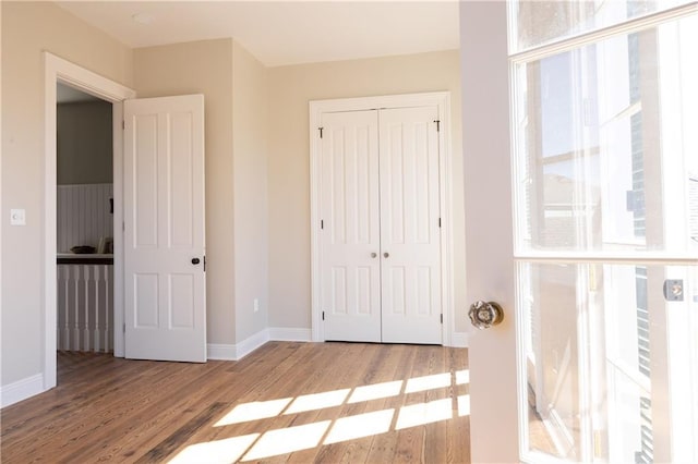 unfurnished bedroom featuring a closet, baseboards, and wood finished floors