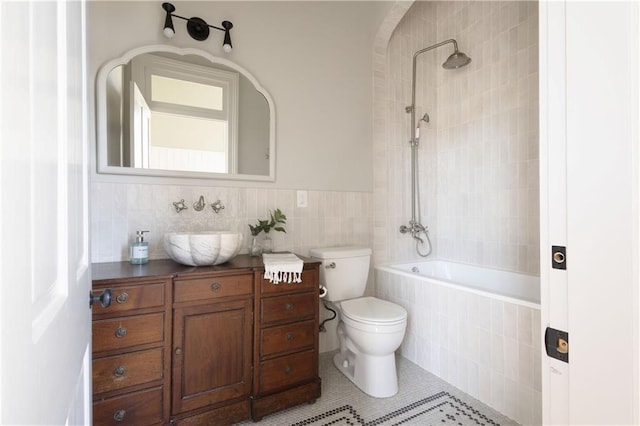 full bath with tile walls, toilet, tile patterned floors, vanity, and tiled shower / bath