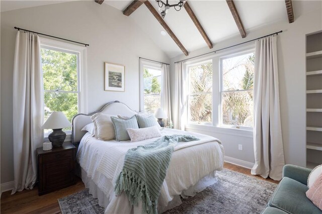 bedroom featuring lofted ceiling with beams, multiple windows, wood finished floors, and baseboards