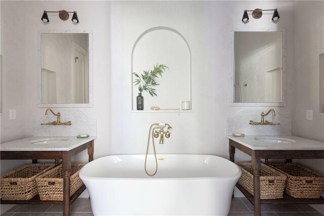 bathroom featuring tile patterned flooring, a soaking tub, and a sink