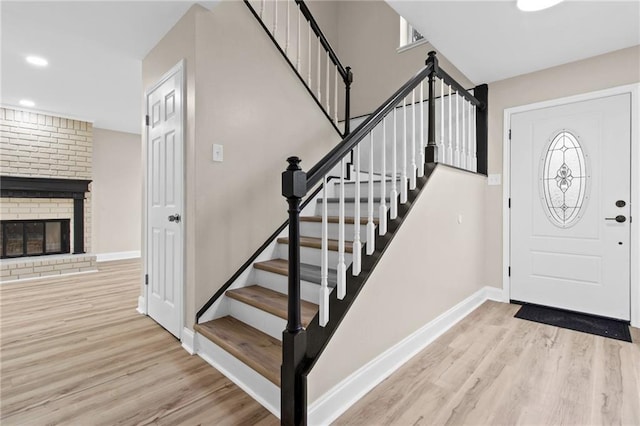 foyer featuring a brick fireplace and light hardwood / wood-style flooring