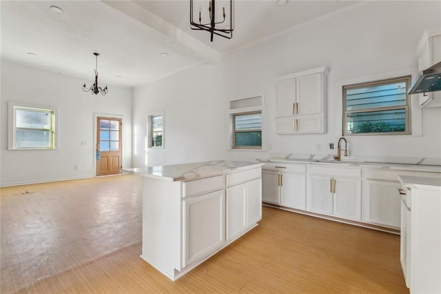 kitchen featuring a kitchen island, decorative light fixtures, an inviting chandelier, light hardwood / wood-style floors, and white cabinetry