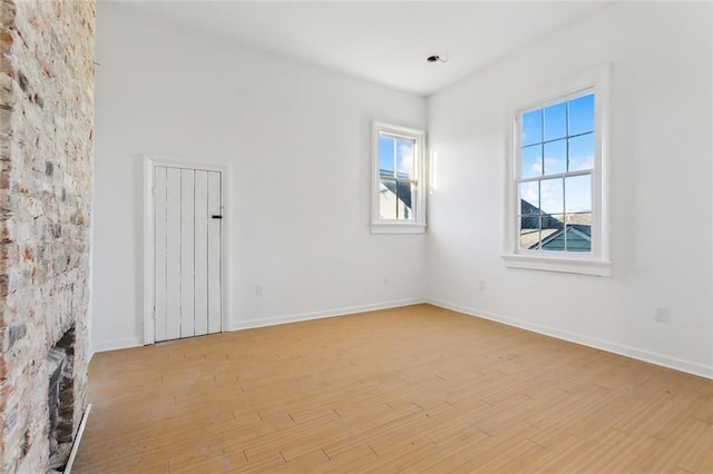 spare room featuring a fireplace and light wood-type flooring