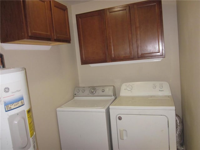 clothes washing area with cabinets, washer and clothes dryer, and water heater