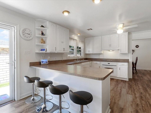 kitchen featuring kitchen peninsula, oven, white cabinetry, and dark wood-type flooring