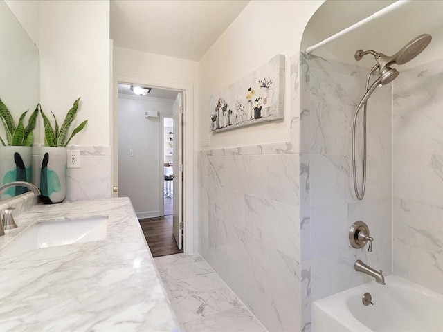 bathroom with tiled shower / bath combo, tile walls, and vanity