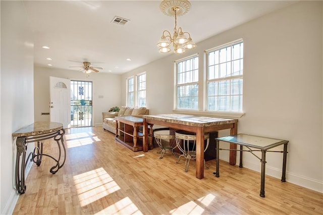 dining area featuring light hardwood / wood-style floors and ceiling fan with notable chandelier