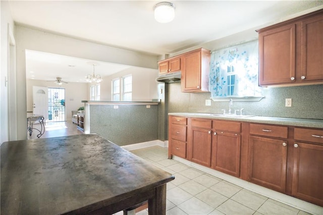 kitchen with backsplash, ceiling fan with notable chandelier, sink, light tile patterned floors, and pendant lighting