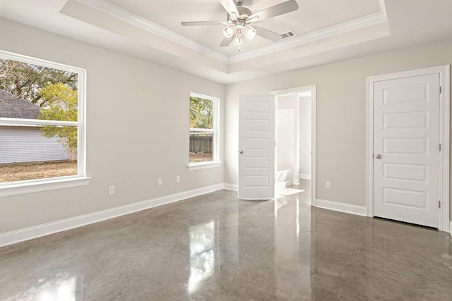 unfurnished bedroom with a tray ceiling, ensuite bathroom, crown molding, and ceiling fan