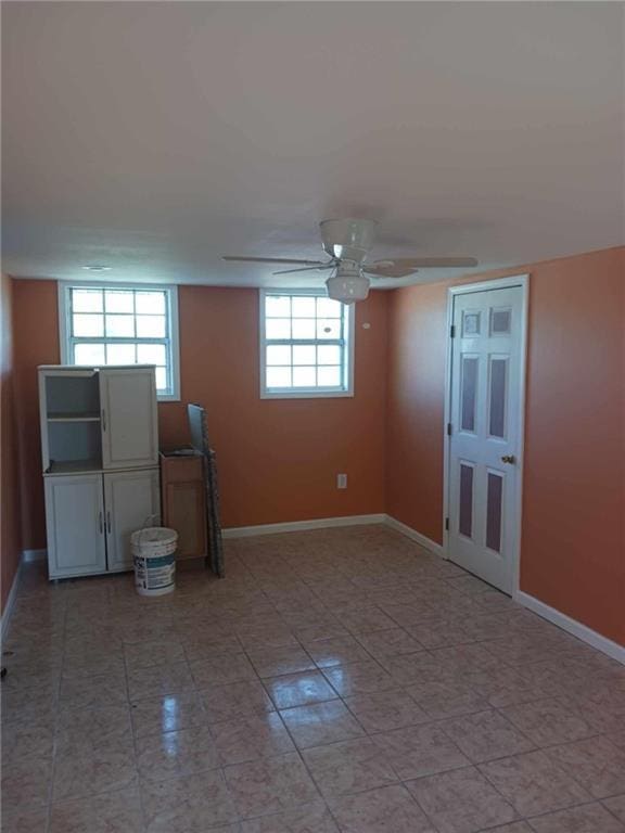 basement with a wealth of natural light and ceiling fan