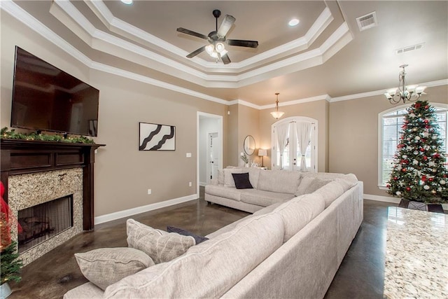 living room with a raised ceiling, a high end fireplace, ceiling fan with notable chandelier, and ornamental molding