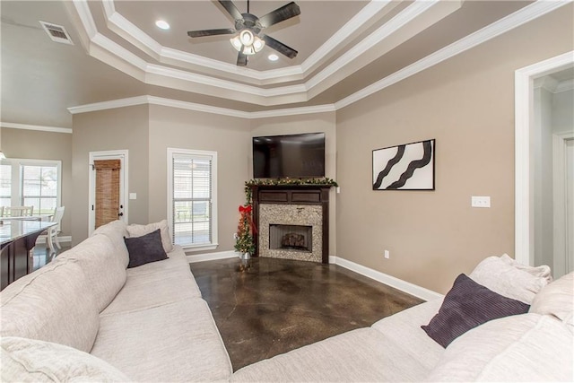 living room featuring ceiling fan, a raised ceiling, and crown molding