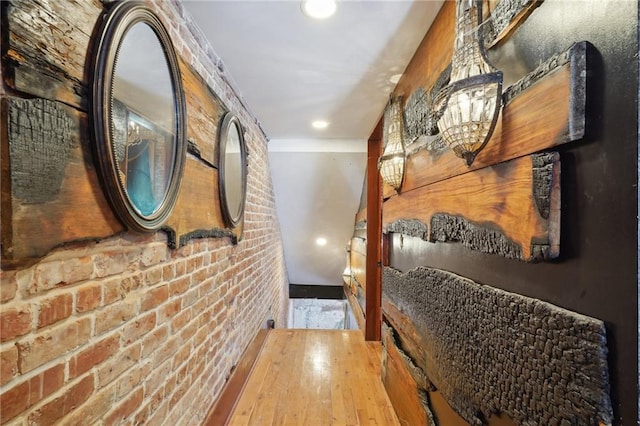 hallway with hardwood / wood-style flooring and brick wall