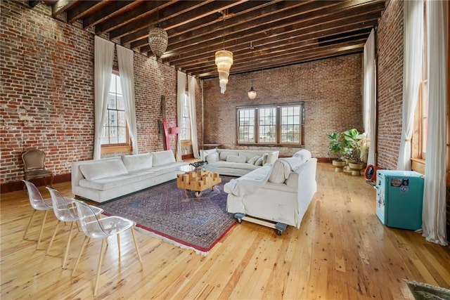 unfurnished living room featuring plenty of natural light, wood-type flooring, and brick wall