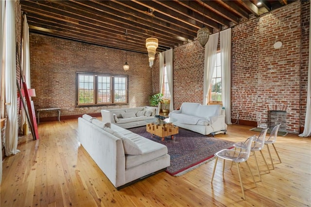 living room with brick wall, wood-type flooring, and a high ceiling