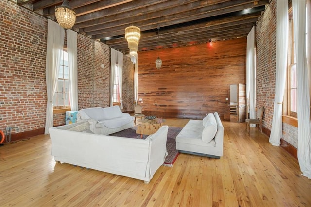 living room featuring beam ceiling, light wood-type flooring, wooden walls, and brick wall