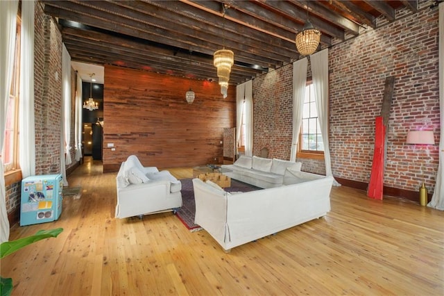 living room with beam ceiling, brick wall, and light hardwood / wood-style flooring