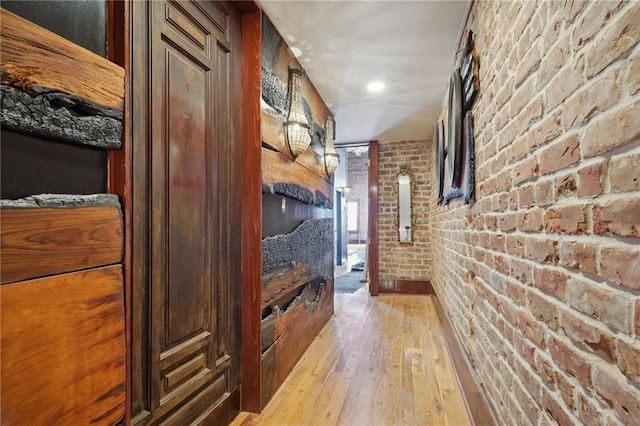 hall featuring light hardwood / wood-style floors and brick wall