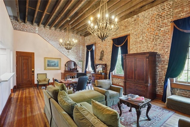 sitting room with hardwood / wood-style flooring, a towering ceiling, beamed ceiling, and brick wall