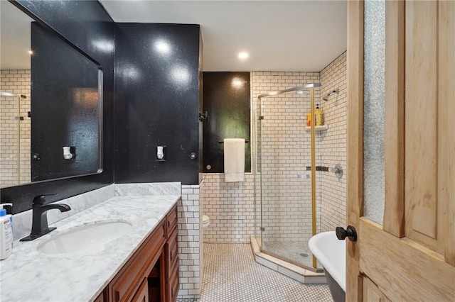 bathroom with walk in shower, tile patterned floors, toilet, vanity, and tile walls