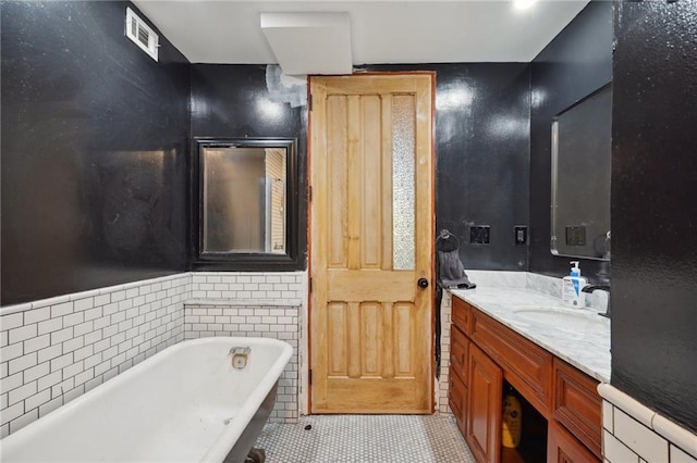 bathroom with tile patterned flooring, vanity, a bath, and tile walls