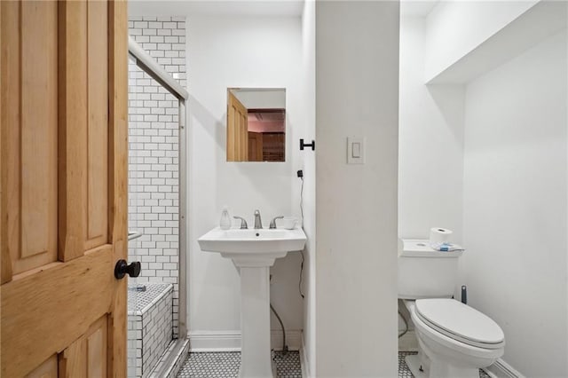 bathroom with tile patterned floors, tiled shower, toilet, and sink