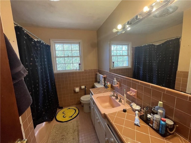 bathroom with tile patterned flooring, tile walls, toilet, vanity, and a shower with shower curtain